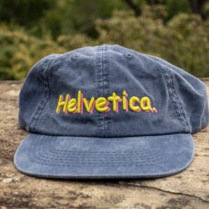 Faded navy dad cap displaying the word "Helvetica" in the Comic Sans font. New cap, funny cap, camper cap, washed cotton, Irony, Humor, meme, Brass clasp.