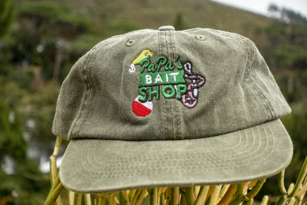 Faded olive green dad cap displaying a logo for a fictional bait and tackle shop, called "Papa's Bait Shop". Everyone loves a vintage fishing cap. New cap, funny cap, camper cap, washed cotton, Irony, Humor, meme, Brass clasp. Fishing hat.